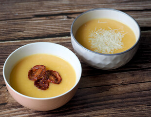 two plates with pumpkin puree soup on a brown dark wooden table. side view . lunch at home. vegan