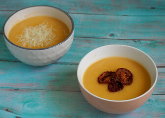 on the blue table are two bowls of pumpkin puree soup. dinner. healthy eating