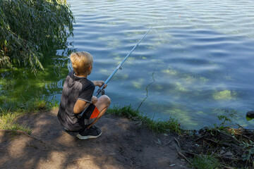 A teenager holds a fishing rod and watches a fish nibble. Sport fishing on the river in summer.