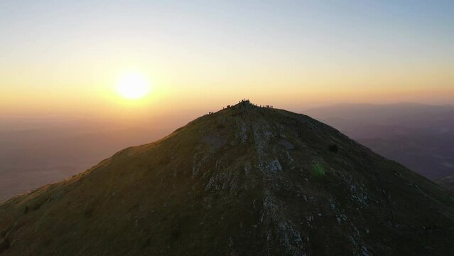The first rays of the rising sun above Rtanj mountain peak with silhouetes of hikers enjoy sunrise