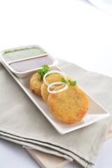 Indian deep fried round potato snack hash brown with green yogurt and red chilli sauce breakfast on white background asian chef appetiser halal bakery food restaurant pastry menu for cafe