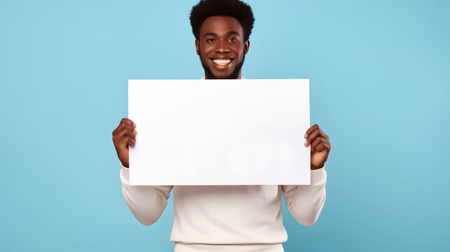 a handsome black african american man holding a blank placard sign poster paper in his hands. empty space for editing and ads. isolated on pastel blue background.