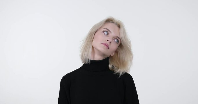 A Caucasian woman stands against a white background, expressing her profound boredom. With a yawn and a stretch, she conveys her longing for excitement and stimulation