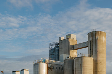Outdoor exterior view of big rough concrete plant against blue sky.