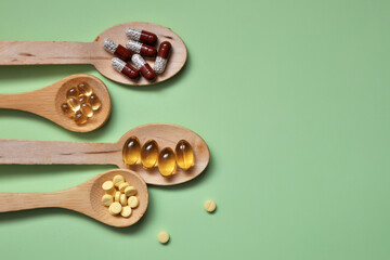 Tablets, capsules, dietary supplements, vitamins in wooden spoons. Medical background
