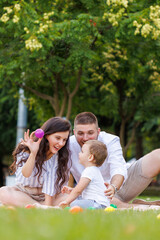 Fototapeta premium Young parents having fun with their little son whille on a picnic