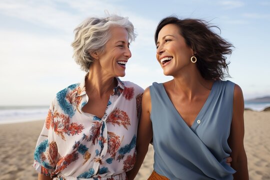 a photo of two diverse middle-aged mature women in modern stylish clothes smiling, on a vacation at the seaside or beach, mature friendship representation.