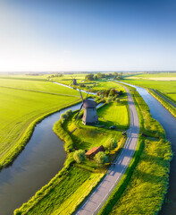 A drone view of windmills in Holland. Windmills on the banks of canals. Agricultural fields and pastures. Aerial view. Summer landscape in the Netherlands.
