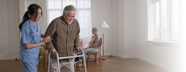 nurse woman walking with senior man with mobility walker in living area of nursing home senior...