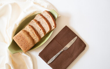 Brown bread slices with a knife on a white background flat lay