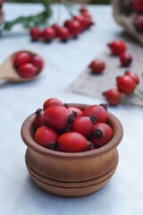 Berries of rosehip in a small wooden bowl. Healthy ingredient. Alternative medicine and herbal therapy concept. Side view, place for text copy space.                