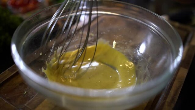 Breaking eggs with a whisk in a mixing bowl