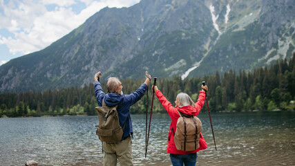 Rear view of senior couple hiking together in autumn mountains.