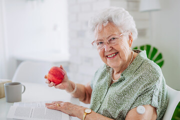 Diabetic senior patient using continuous glucose monitor to check blood sugar level at home.