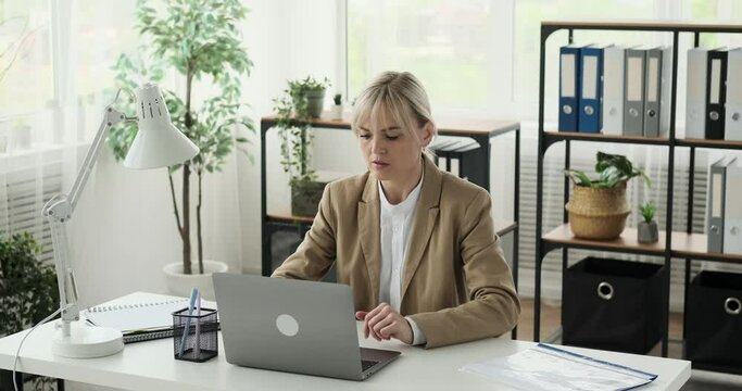 Unsatisfied businesswoman typing on her laptop at her workplace. With a serious expression and determined keystrokes, she displays her dissatisfaction with the current situation.