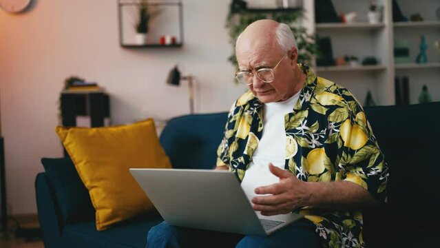 Funny senior man having problems with his laptop, computer crashes, technology