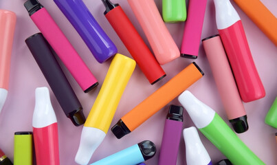 Set of multicolor disposable electronic cigarettes on a pink background.