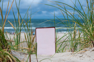 Empty white board in the sand dunes at the beach.