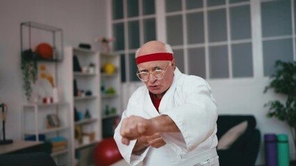 Portrait of funny senior man practicing martial arts in white kimono, humor
