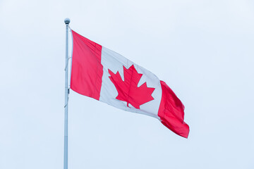 Canadian flag with maple leaf on the pole motion movement. Flag of Canada flying against a summer sky. Canadian flag waving on the wind.