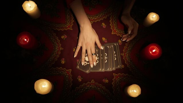 Top view, woman hands placing a fan of tarot cards on the table and open one card, showing to the camera.