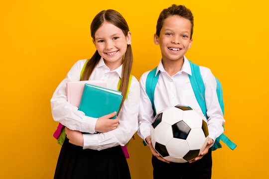 Photo of two lovely schoolkids prepare for school year hold soccer ball textbooks isolated on bright color background