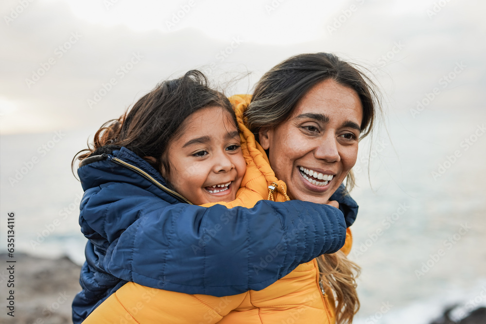 Wall mural happy latin mother and daughter having fun together outdoor during winter time