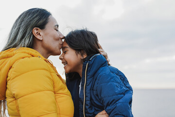 Latin mother having tender moment with little daughter outdoor during winter time