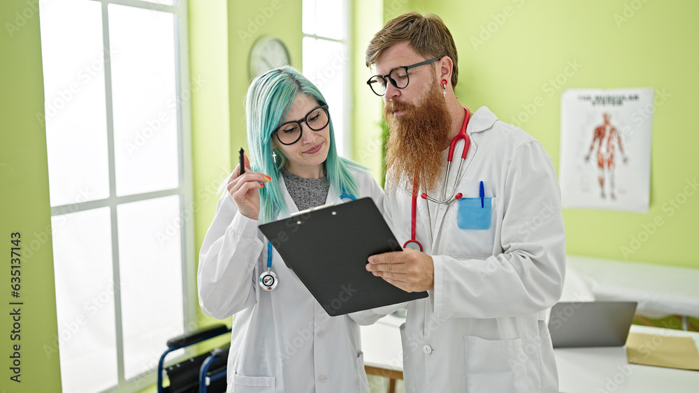 Wall mural man and woman doctors reading medical report speaking at clinic