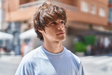 Young blond man looking to the side with serious expression at street