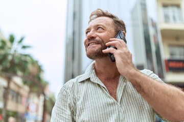 Middle age man smiling confident talking on the smartphone at street