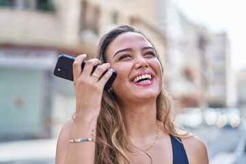 Young beautiful hispanic woman smiling confident listening audio message by the smartphone at street