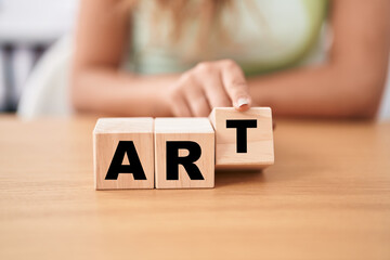 Naklejka premium Young woman holding cubes with art word on the table