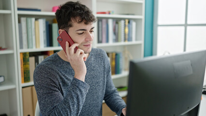 Young hispanic man student using computer studying at library university