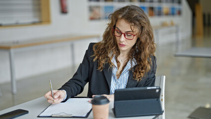 Young woman business worker using touchpad writing on document at the office