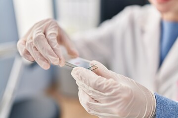 Young blonde woman scientist holding blood sample at laboratory