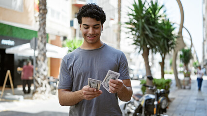 Young latin man smiling confident counting dollars at street