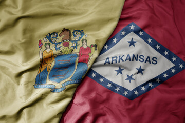 big waving colorful national flag of arkansas state and flag of new jersey state .