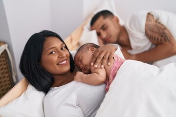 Hispanic family lying on bed at bedroom