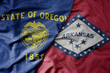 big waving colorful national flag of arkansas state and flag of oregon state .