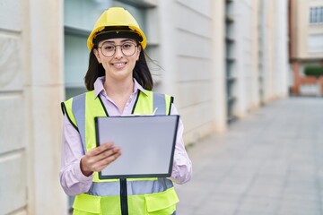 Young hispanic woman architect write on document at street