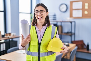 Hispanic girl architect holding build project blueprints winking looking at the camera with sexy...