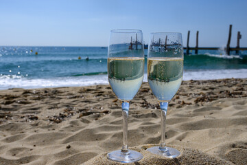Summer time in Provence, two glasses of cold champagne cremant sparkling wine on famous Pampelonne sandy beach near Saint-Tropez in sunny day, Var department, France