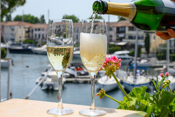 Drinking of French brut champagne sparkling wine in glasses, club party in yacht harbour of Port Grimaud near Saint-Tropez, French Riviera vacation, France