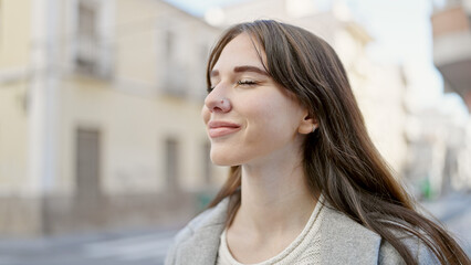 Young hispanic woman standing with closed eyes at street