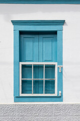 Obraz premium Decorative, colonial, blue, vintage window on a white wall in the countryside of Rio de Janeiro, Brazil.