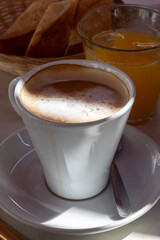 White cup of coffee latte served in outdoor cafe in France