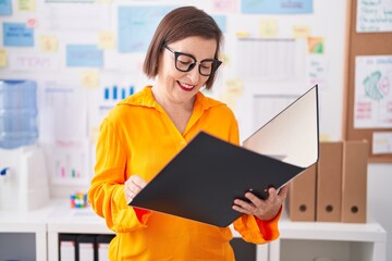 Middle age woman business worker reading document at office