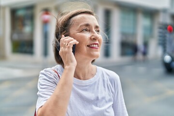 Middle age woman smiling confident talking on the smartphone at street