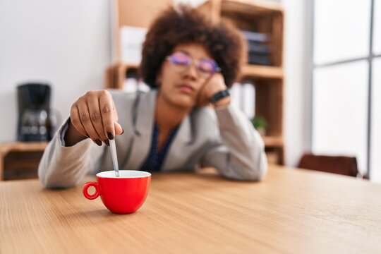 African american woman business worker with tired expression stiring the coffee at office